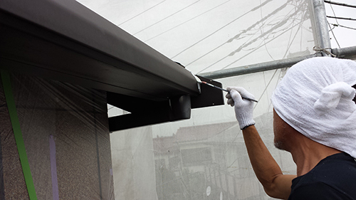 koushin_03hafu | 外壁塗装は神奈川県横浜市の塗装職人 Worker wearing a white head wrap and gloves, painting the edge of a storefront frame with a brush