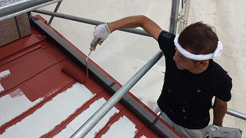 koushin_04geyanenaka | 外壁塗装は神奈川県横浜市の塗装職人 Worker on scaffolding painting a red metal roof with white paint using a roller.